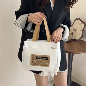 Detailed close-up of a Japanese style white canvas handbag with brown handles and a vintage patch