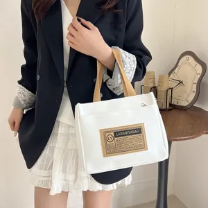Macro view of white canvas bento handbag featuring stylish brown straps and logo patch
