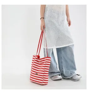 Vista de cuerpo completo de una modelo con un bolso tote de lona a rayas rojas y blancas