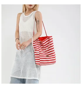 Foto de modelo con un gran bolso tote de lona a rayas rojas y blancas en un estilo casual.