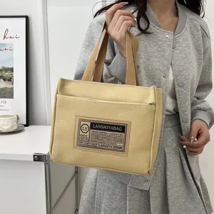 Detailed view of the minimalist yellow canvas tote bag being held for daily use