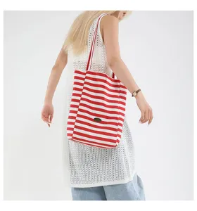 Modelo con un bolso tote de lona a rayas rojas y blancas y un vestido de malla blanco.