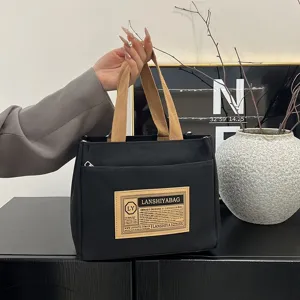 Minimalist black canvas tote bag with brown woven straps for daily commuting or lunch