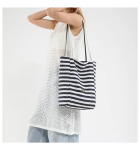 Bolso tote casual de lona a rayas azul marino y blanco, mostrado por una modelo al hombro.