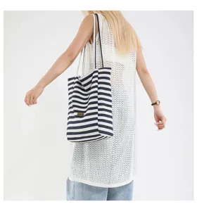 Modelo caucásica con un bolso tote de lona a rayas azul marino y blanco en estilo casual