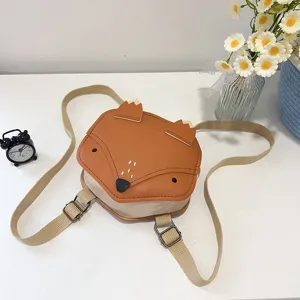Detail view of a cute fox-shaped kids backpack with beige adjustable straps on a white desk