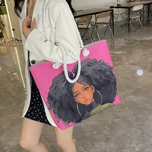 Detalle del bolso tote rosa con estampado de chica negra y asas de cuerda gruesa.