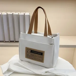 Macro view of minimalist white canvas tote bag with vintage brown label and handles