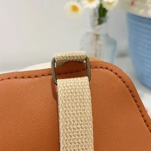 Detail view of the bronze metal strap attachment on a brown faux leather backpack