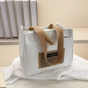 Close-up of a stylish minimalist white canvas tote bag with a brown brand patch