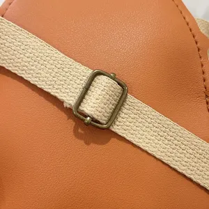 Detail of children's backpack showing textured orange faux leather and strap buckle