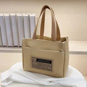 Beige Japanese style canvas handbag featuring brown handles and front brand label detail
