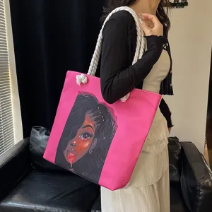 Detalle de bolso tote rosa con estampado de chica negra y asas de cuerda blancas