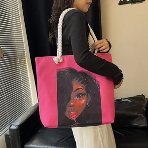 Detalle del bolso tote rosa con estampado de chica negra y asas de cuerda gruesa blanca.