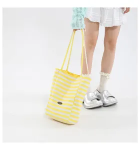 Detalle de un bolso de lona con rayas amarillas combinado con un conjunto informal