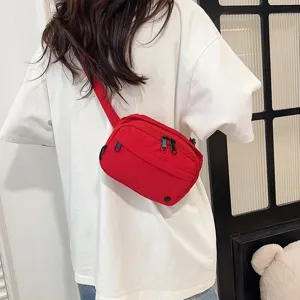 Primer plano de un bolso bandolera de tela oxford rojo vibrante sobre una camiseta blanca