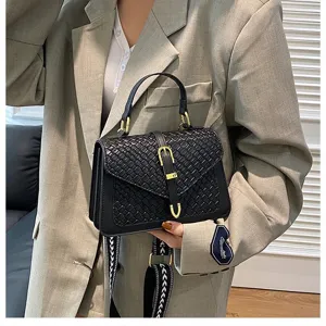 Bolso bandolera negro con textura tejida sostenido por una modelo en blazer gris