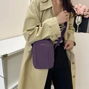 Primer plano detallado de un bolso bandolera de nailon púrpura impermeable para mujer.