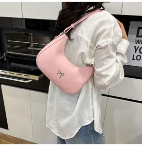 Detailweergave van roze onderarmtas met zilveren strik op de schouder van model.