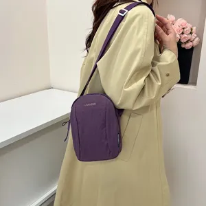 Modelo con un bolso bandolera de nailon morado sobre una gabardina beige clásica