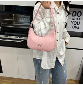 Detail van de roze zadel tas met strik, gestyled met een wit overhemd en een spijkerbroek