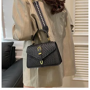 Primer plano de un bolso negro con textura trenzada, hebilla dorada y correa moderna