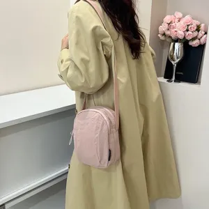 Vista detallada de una modelo con un bolso bandolera de nailon rosa impermeable