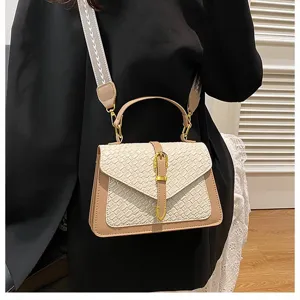 Vista detallada de bolso beige con textura tejida y correa de hombro ancha elegante