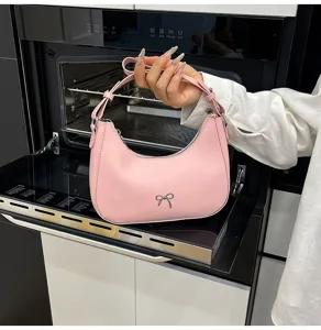 Gedetailleerd overzicht van een roze hobo-tas met zilveren strik, vastgehouden.