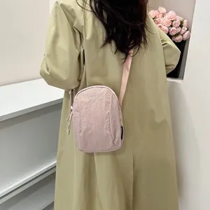 Vista trasera de un pequeño bolso bandolera de nailon rosa para mujer, diseño minimalista