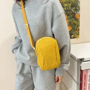 Vista detallada del bolso bandolera de nailon amarillo con chándal gris informal