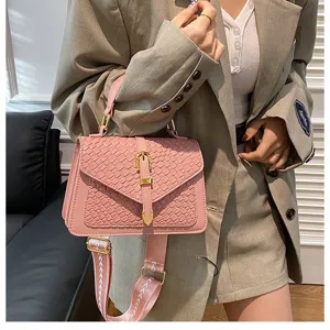 Detalle de un bolso bandolera rosa con patrón trenzado y correa ancha de moda