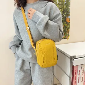 Bolso bandolera informal de nailon amarillo llevado por una modelo en entorno real