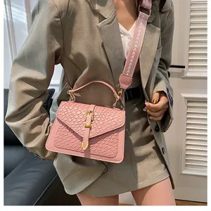 Primer plano de un bolso bandolera trenzado rosa con una correa de hombro decorativa