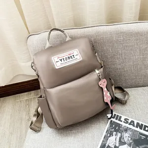 Gedetailleerd beeld van een kaki Oxford stoffen rugzak met een schattige kattenhanger