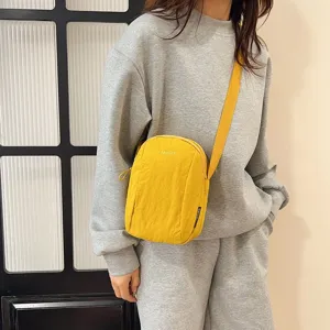 Vista de estilo de vida de un bolso bandolera de nailon amarillo impermeable con modelo.