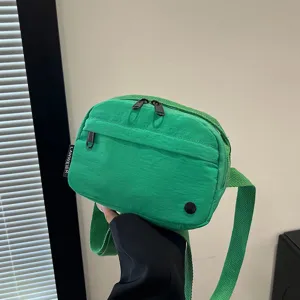 Detalle de un bolso bandolera de nailon verde impermeable con prácticos cierres