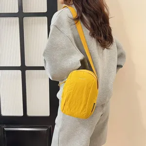 Detalle del bolso bandolera amarillo de nailon impermeable con bordado LANWEIER en traje gris