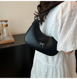 Elegante zwarte schoudertas met zilveren strikdetail in een lifestyle-opname