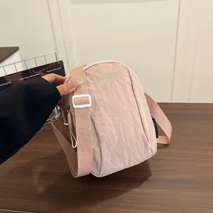 Vista detallata de un bolso bandolera de nailon rosa impermeable con el logo LANWEIER.