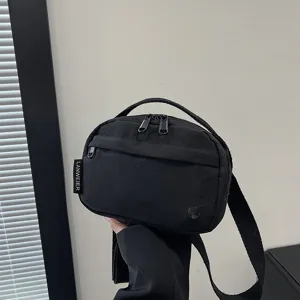 Vista detallada de un bolso bandolera de tela oxford impermeable negro con etiqueta