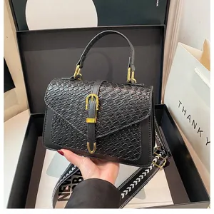 Detalle de cerca del bolso bandolera negro con patrón trenzado en caja de regalo