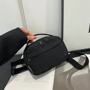 Vista detallada de la riñonera minimalista negra de tela Oxford impermeable con marca.