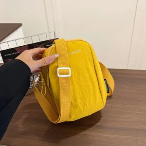 Detalle de bolso bandolera de nailon amarillo impermeable con hebilla blanca ajustable