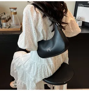 Stijlvolle zwarte hobo schoudertas met zilveren strik detail gedragen door een model.