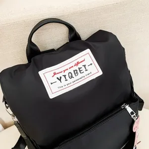 Detailopname van zwarte waterdichte oxford rugzak met wit YIQBEI-merklogo