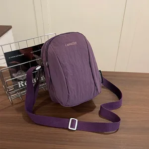 Vista detallada de un bolso bandolera de nailon morado impermeable con correa ajustable
