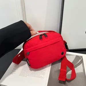 Vista detallada de un bolso bandolera rojo de tela Oxford impermeable con cremalleras negras