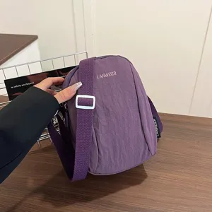 Vista detallada de un bolso bandolera de nailon violeta impermeable con correa