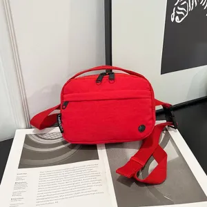 Primer plano de un bolso bandolera rojo de tela oxford impermeable sobre una revista.